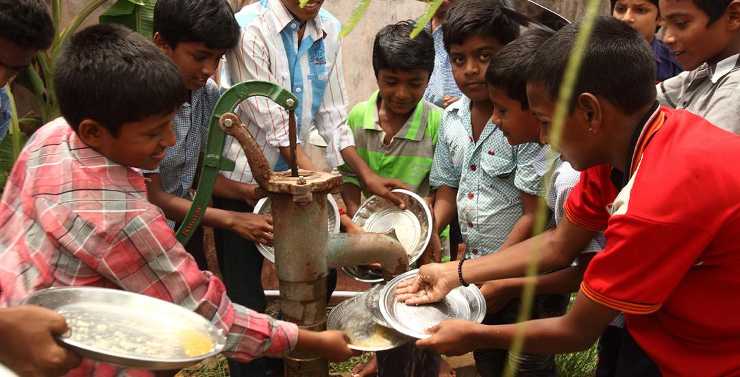 Young group cleaning plates in India